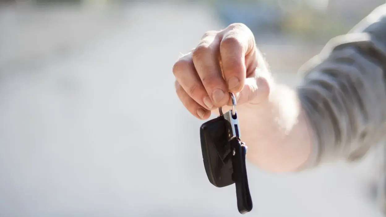 Mão a segurar chave de carro com comando remoto