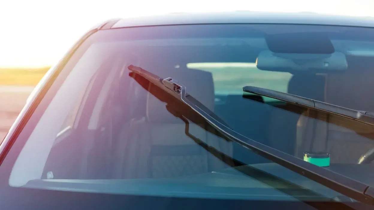 Limpa para-brisas levantados num carro estacionado ao sol