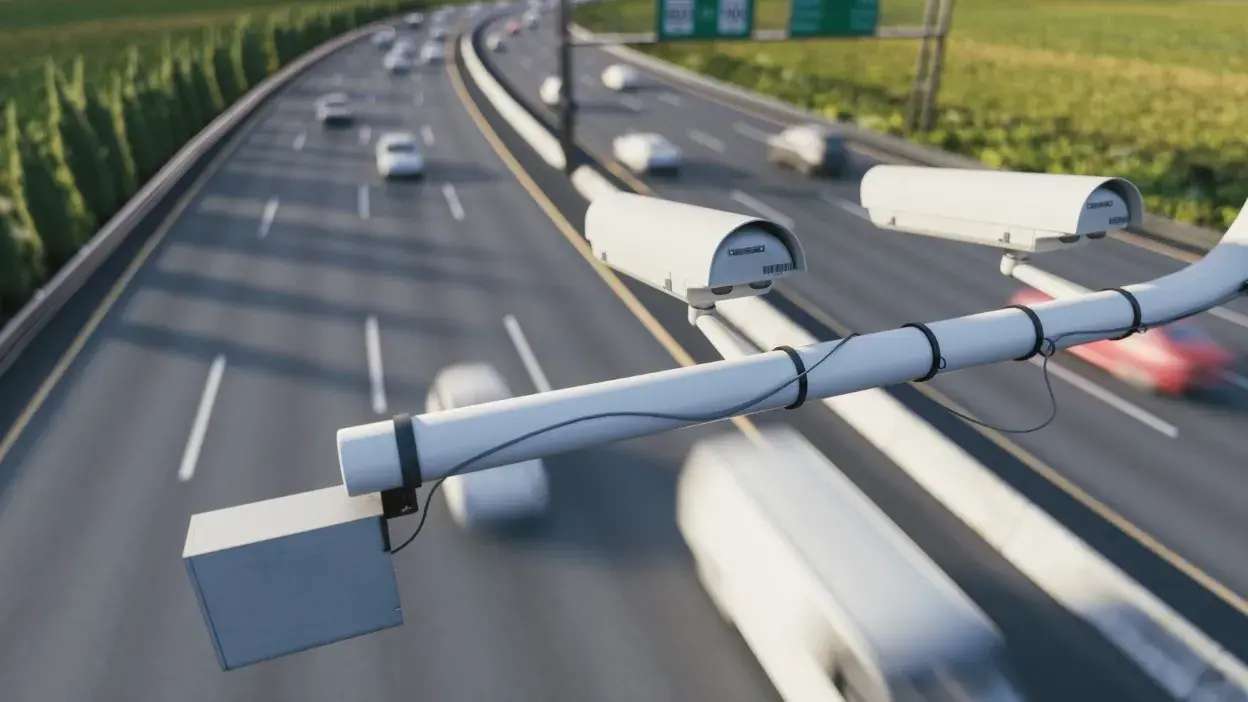Câmaras de controlo de velocidade instaladas numa autoestrada com veículos em movimento desfocado.